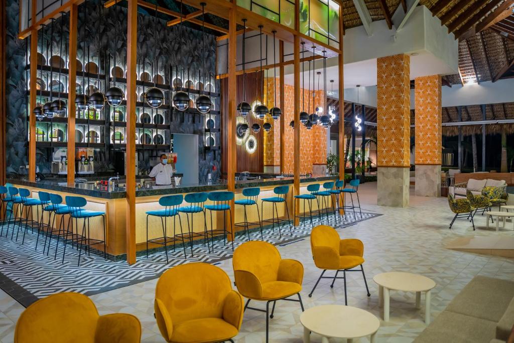 Mūsdienīgs bārs ar stilīgām krēsliem un lielu galdu, rotāts ar krāsainām sienām un modernu apgaismojumu. Telpā ir plaša atpūtas zona ar ērtām mēbelēm.