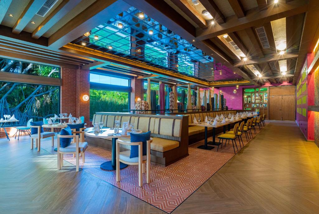 Mūsdienīgs restorāna interjers ar plašām telpām, ērtām mēbelēm un dzīvīgu krāsu paleti. Lielie logi nodrošina dabisko apgaismojumu un skatu uz dārzu.