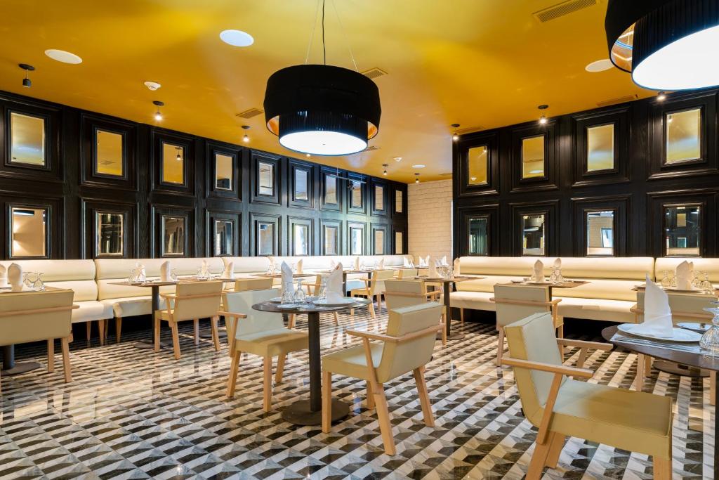 Mūsdienīgs restorāns ar elegantiem melniem un baltajiem interjera elementiem, kas veidots ar stilīgām mēbelēm un atspoguļojošām virsmām. Telpa ir apgaismota ar modernām lampām un izceļas ar grafisku grīdas dizainu.