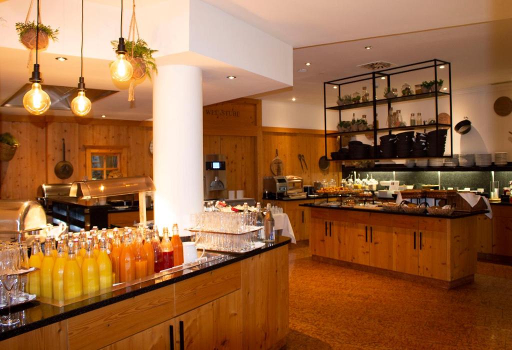 Mūsdienīga kafejnīca ar koka interjeru, elegantiem gaismas ķermeņiem un bagātīgu ēdienu izvēli uz galdiem. Svaigi dzērieni un gardumi ir izlikti uz melna galda, radot mājīgu atmosfēru.