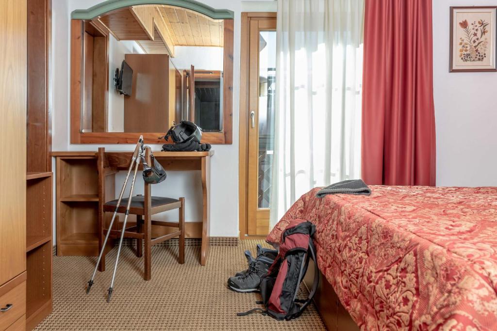 Mājīga viesnīcas numuriņa iekārtojums ar gultu, rakstāmo un sporta aprīkojumu, tostarp zābakiem un nūjām. Logā caur caurspīdīgām aizkariem ieplūst dabiska gaisma.
