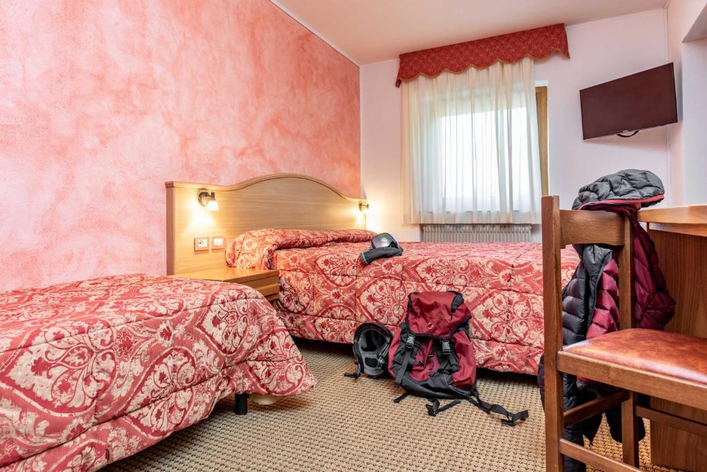 Kopmītne ar divām gultām un siltām krāsām, aprīkota ar televizoru un rakstāmgaldu, apņemta ar somām un apģērbu.