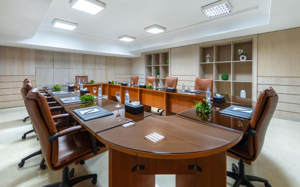 Moderns konferenču telpa ar garu galdu, ērtām krēslām un dekoratīvām augu kompozīcijām. Interjers ir gaišs un profesionāls, piemērots biznesa sanāksmēm.