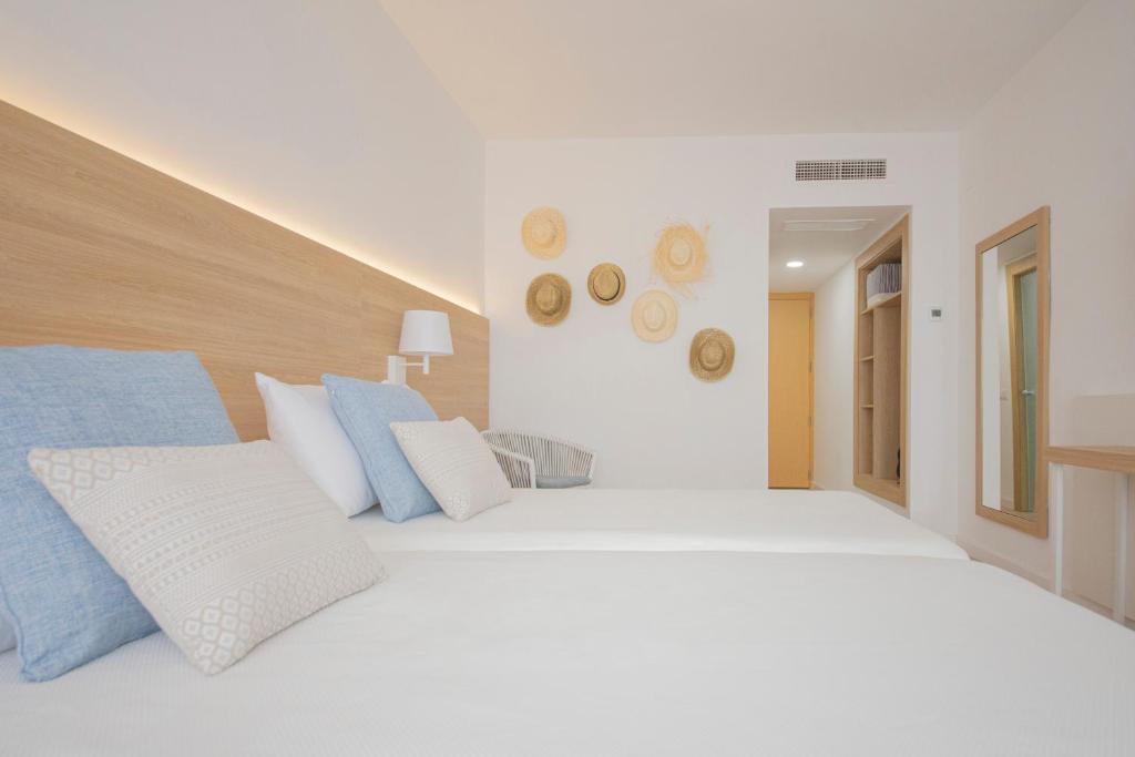 Mūsdienīgs guļamistabas interjers ar divām gultām, kas dekorētas ar spilveniem, un sienas apdari ar salmu cepurēm. Telpa ir gaiša un ērta, ar koka akcentiem un lielu spoguļi.