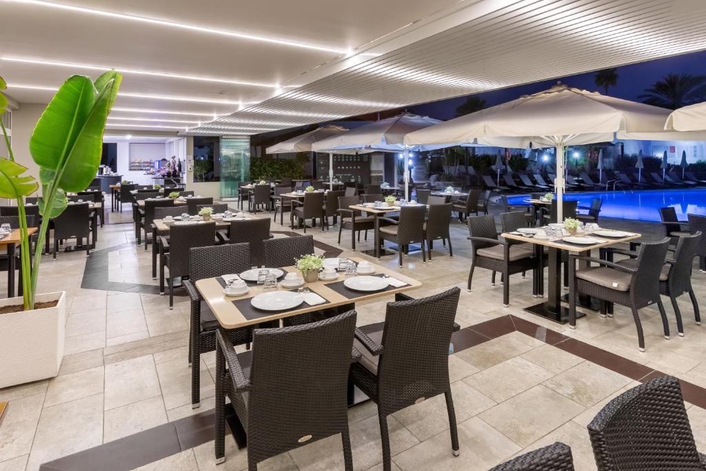 Restorāna terase ar galdiem un krēsliem, apgaismojums un peldbaseins fonā. Ideāla vieta vakariņām brīvā gaisotnē.