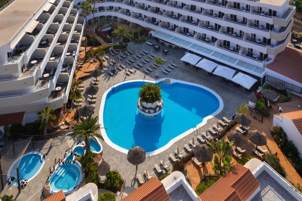 Viesnīcas komplekss ar lielu peldbaseinu un sauļošanās gultām, ko ieskauj tropu augi un viesnīcas ēkas. Peldbaseinā ir centrālais augsts zaļš augs un vairākas mazākas burbuļvannas.