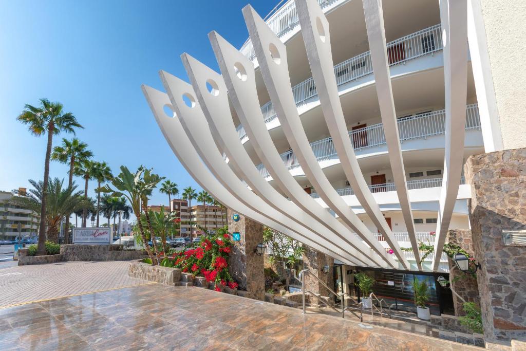 Mūsdienīgas viesnīcas ieeja ar stilīgu arhitektūru, palmu un ziedu apstādījumiem, kas rada relaksējošu atmosfēru. Ideāla vieta atpūtai un brīvdienām.