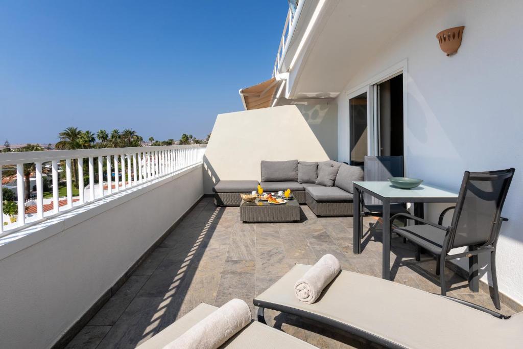 Plaša terase ar mīkstiem dīvāniem un galdu, ideāla relaksācijai zem saules. Skats uz zilo debesu un apkārtējo ainavu.