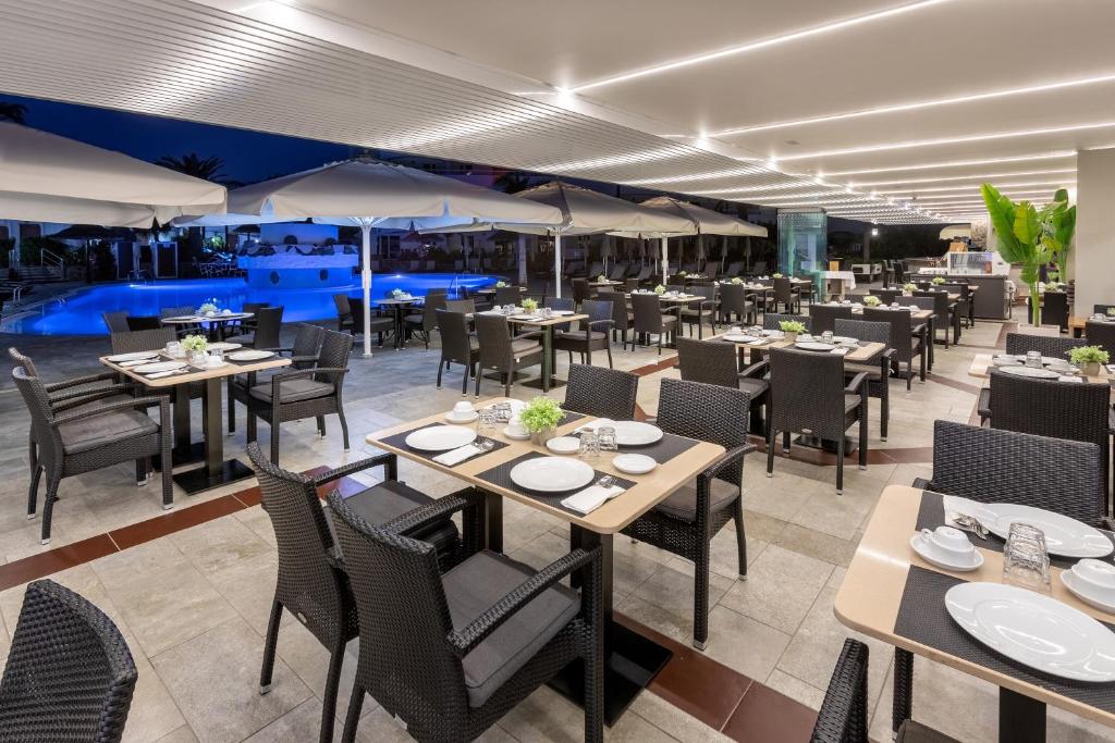 Āra restorāna terase ar elegantām galdiem un krēsliem, apgaismota ar modernām gaismām, blakus peldbaseinam. Ideāla vieta vakariņu baudīšanai.