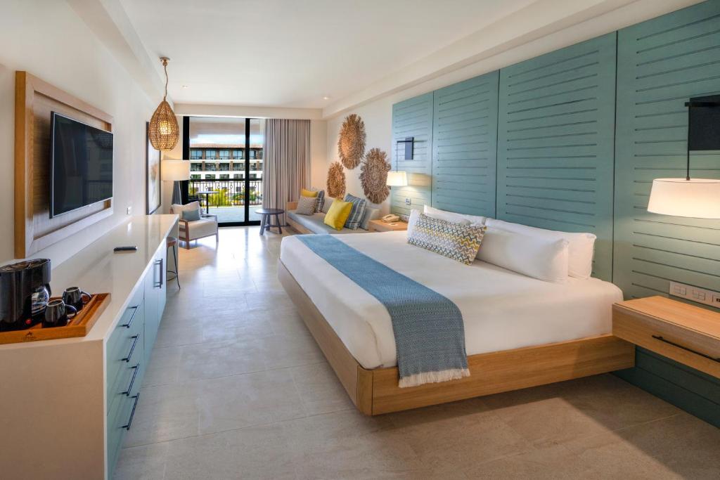 Mūsdienīgs viesnīcas numurs ar plašu gultu, koka mēbelēm un gaišām krāsām, kas rada relaksējošu atmosfēru. Logi ved uz balkonu, no kura paveras skats uz dārzu.