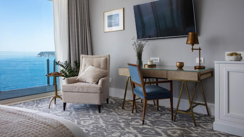 Mūsdienīgs viesnīcas numurs ar skatu uz jūru, ērta atpūtas zona un darba galds. Eleganta interjera dizaina elementi, kas rada relaksējošu atmosfēru.