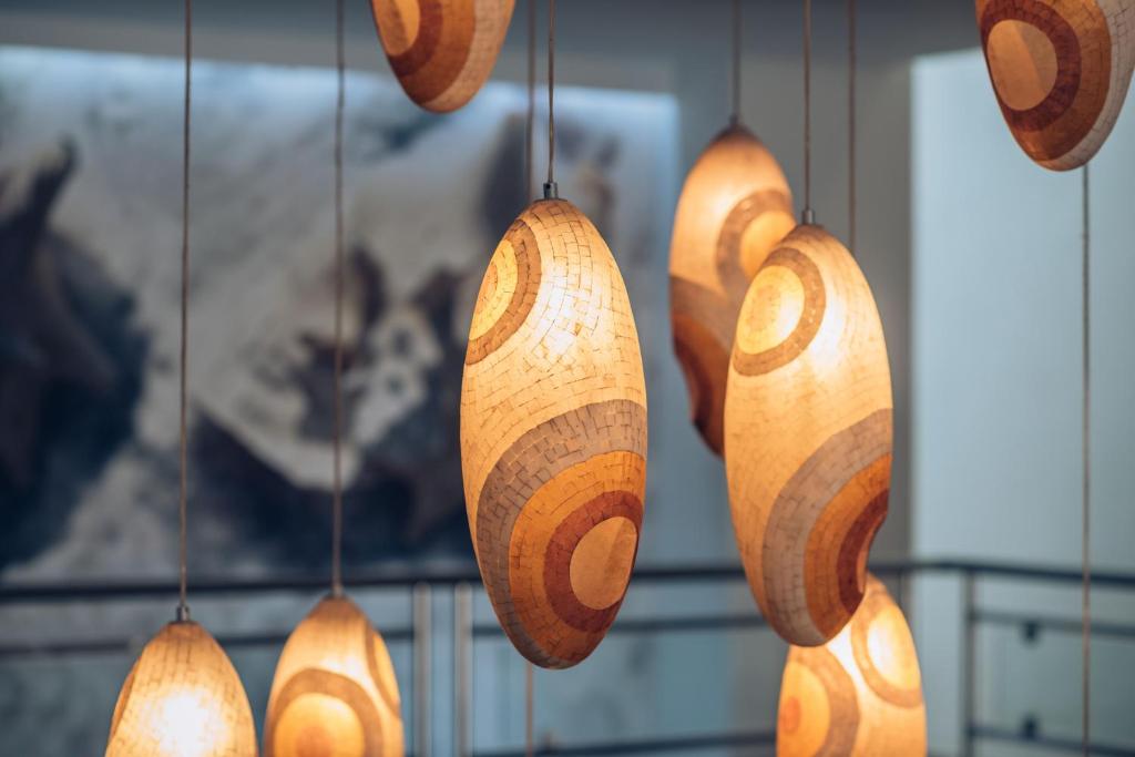 Mūsdienīgi gaismekļi ar ovālām formām un koka rakstiem, kas piekārti pie griestiem, rada siltu un mājīgu atmosfēru.