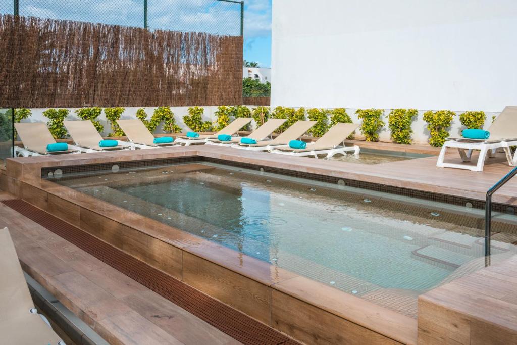 Mūsdienīgs atpūtas baseins ar sauļošanās krēsliem un zaļām dzīvžogiem, kas rada relaksējošu atmosfēru. Ideāla vieta, lai izbaudītu sauli un atpūtu.