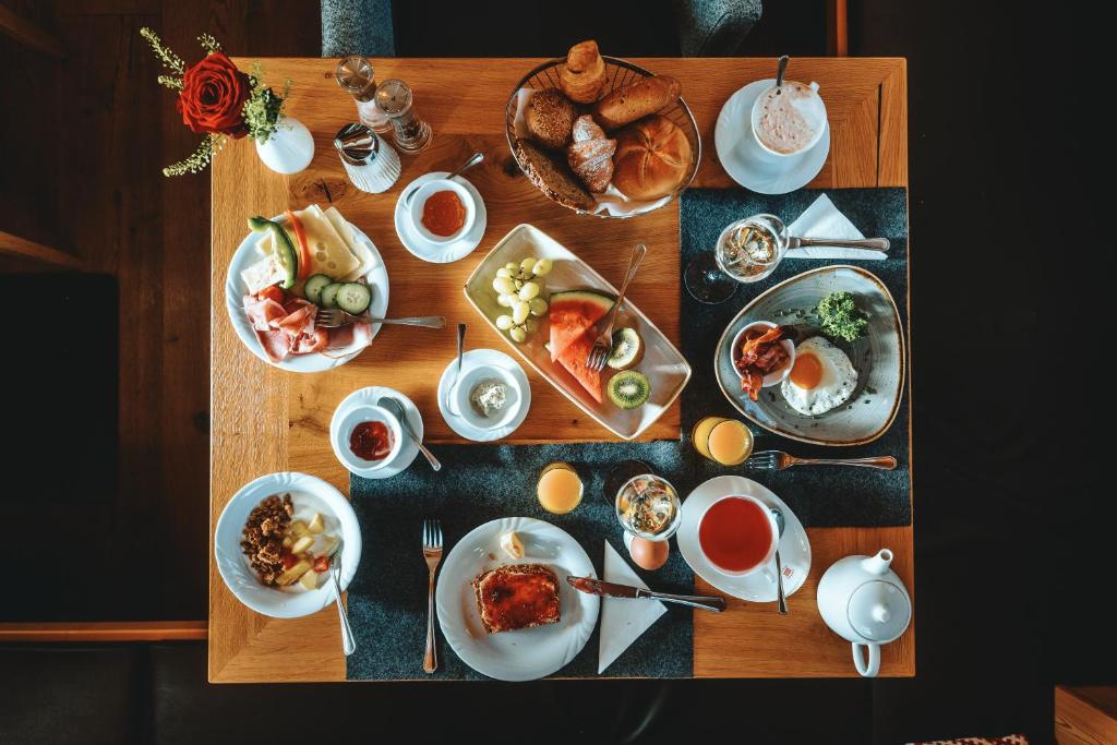Bagātīga brokastu galda kompozīcija, kas ietver dažādus ēdienus, piemēram, augļus, gaļu, maizes izstrādājumus un dzērienus. Ideāla izvēle gardēžiem, kas meklē pilnvērtīgu maltīti.