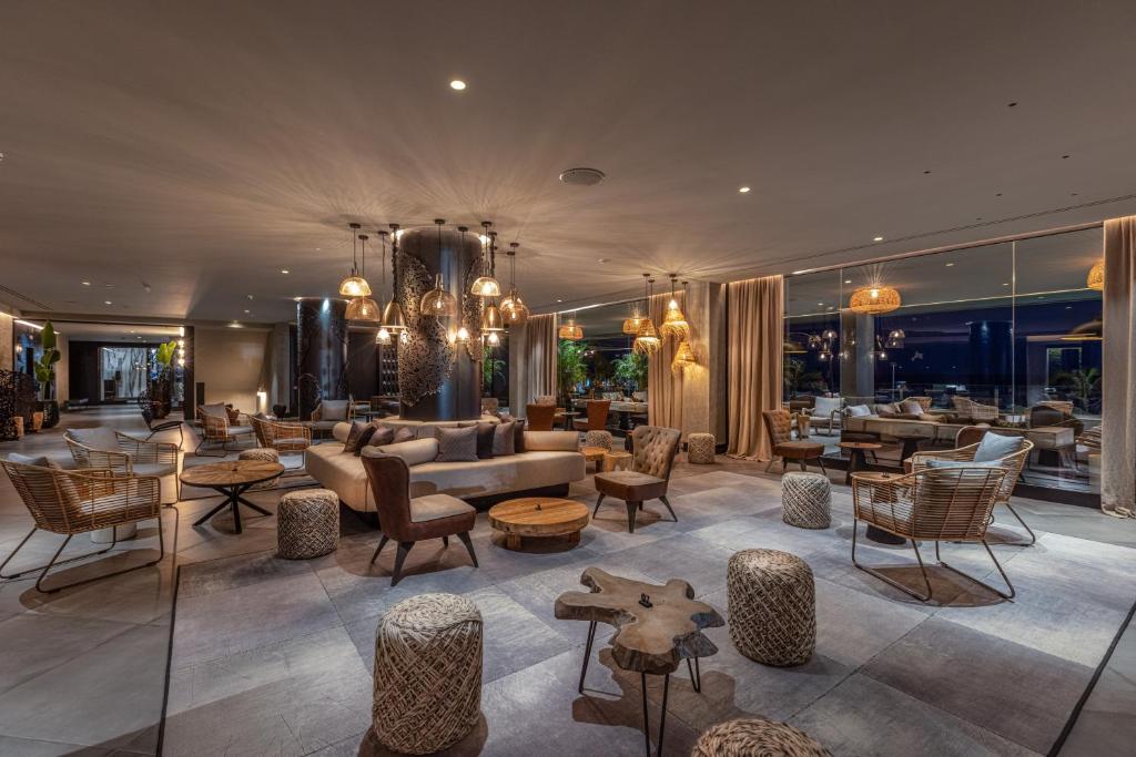 Mūsdienīgs viesnīcas interjers ar ērtām mēbelēm, dabīgām materiālu tekstūrām un siltu apgaismojumu, radot relaksējošu atmosfēru. 