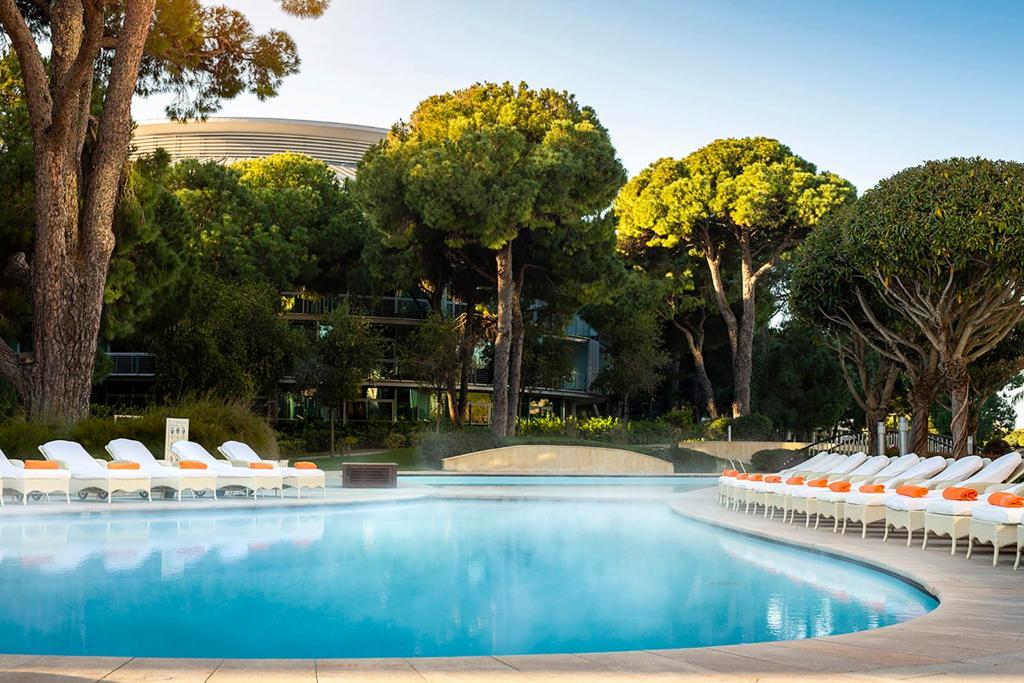 Luksusa viesnīcas baseins ar saulessargiem un kokosriekstu kokiem, radot relaksējošu atmosfēru. Ideāla vieta atpūtai un izklaidei.