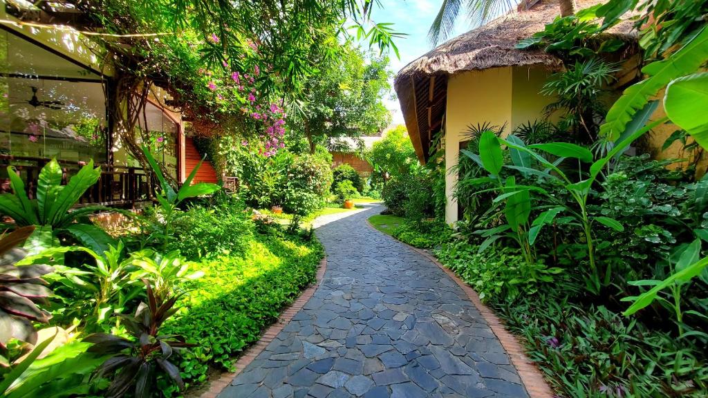 Apzaļumota taka, kas ved cauri sulīgai dārzai ar tropiskām augu sugām un ziediem, starp mājām ar jumtu no salmu. Ideāla vieta relaksācijai un dabas baudīšanai.