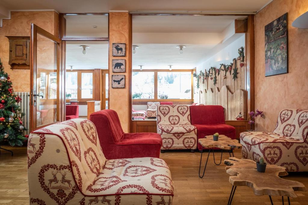 Siltums un mājīgums viesistabā ar sarkaniem dīvāniem un dekoratīvām krēslām, izrotāta ar Ziemassvētku eglīti un mājīgām detaļām.