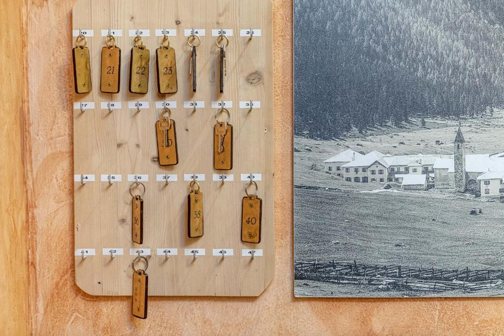 Atslēgu plāksne ar numurētām atslēgām, kas piekārtas uz koka virsmas, blakus vintage fotogrāfijai ar ainavu un mājām.