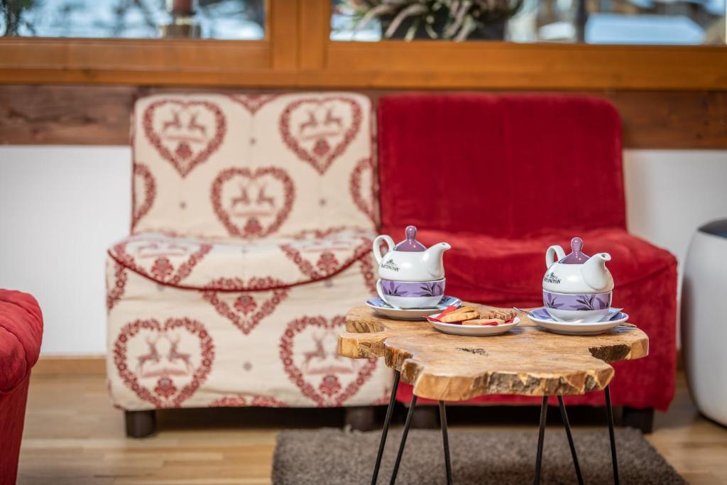 Siltinātā telpa ar ērtām krēslām, koka galdiņu un tējas komplektu, kas papildināts ar cepumiem. Interjers rada mājīgu un aicinošu atmosfēru.