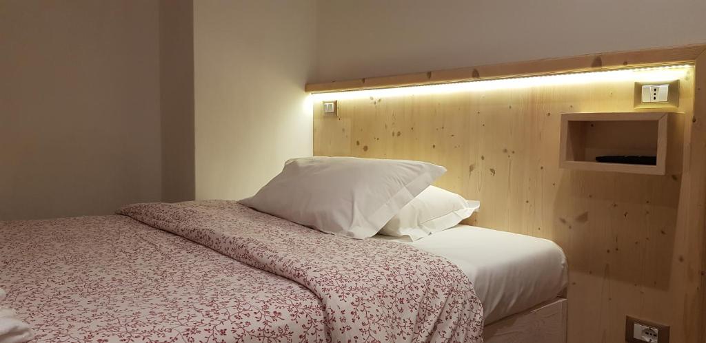 Mūsdienīga guļamistaba ar koka sienu apdari un gaismas elementiem, kas izceļ gultu ar rakstainu gultasveļu.