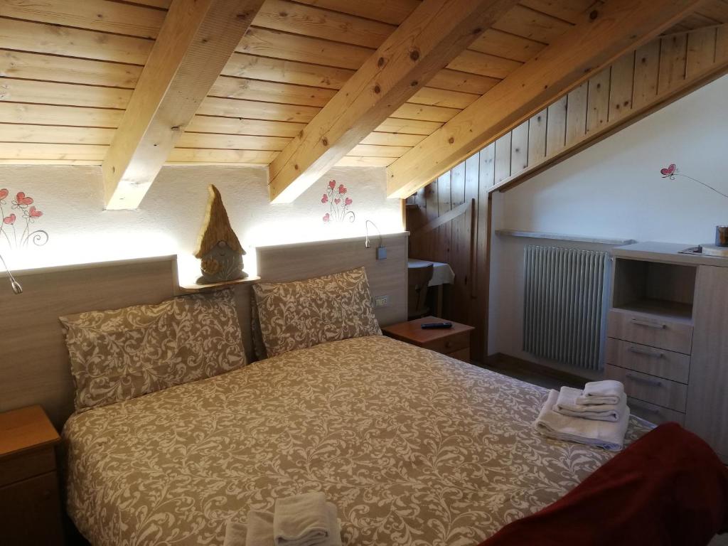 Mūsdienīgs guļamistabas interjers ar koka griestiem, ērtu gultu un maigu apgaismojumu, radot siltu un viesmīlīgu atmosfēru.