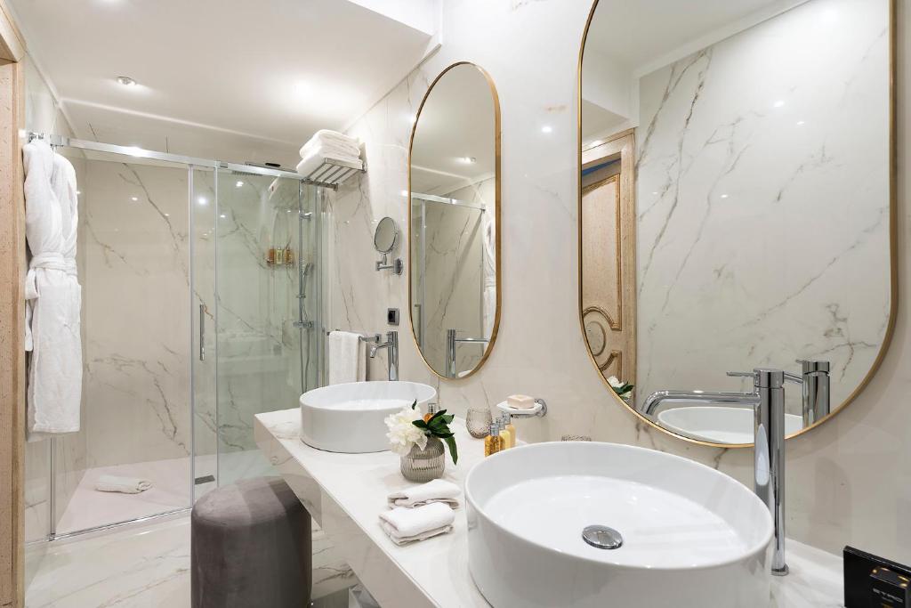 Mūsdienīgs vannas istabas interjers ar marmora sienām, divām apaļām spoguļu virsmām un elegantu izlietni, apvienojot komfortu un stilu.