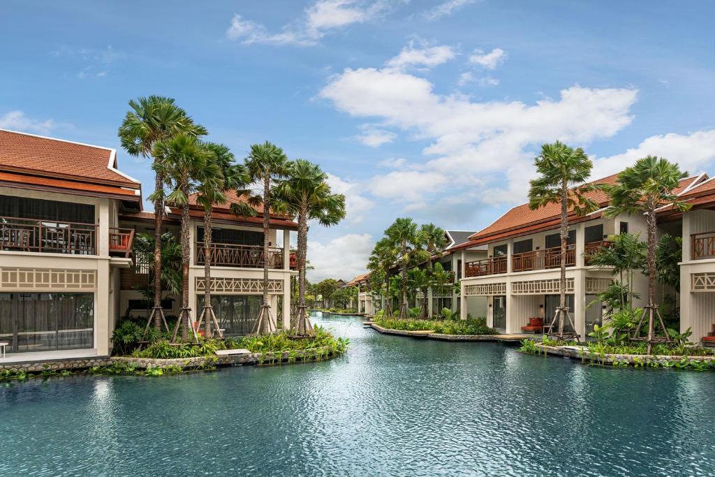 Grand Mercure Khao Lak Bangsak skaists baseins ar palmām un numuriem piekrastē.