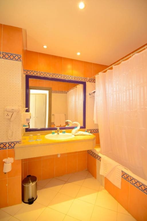 One Resort Aqua Park & Spa vannas istaba ar oranžām flīzēm un spoguli.