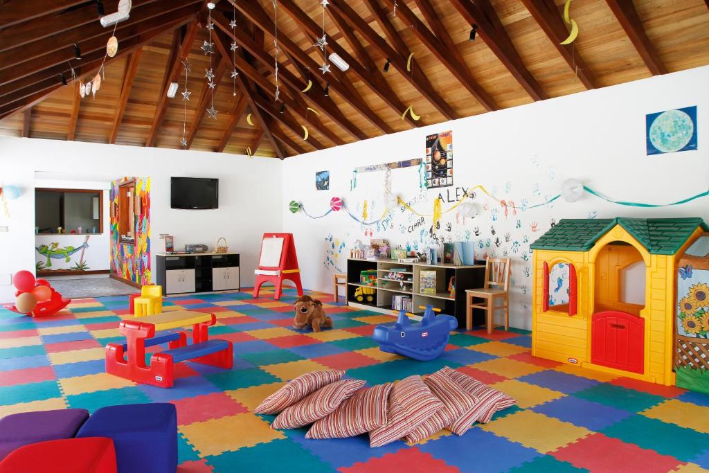 Krāsaina bērnu rotaļu telpa ar mīkstiem paklājiem, rotaļlietām un mājiņu, kas ir piemērota bērnu spēlēm un aktivitātēm. Telpa ir izrotāta ar zvaigznēm un mēness simboliem.