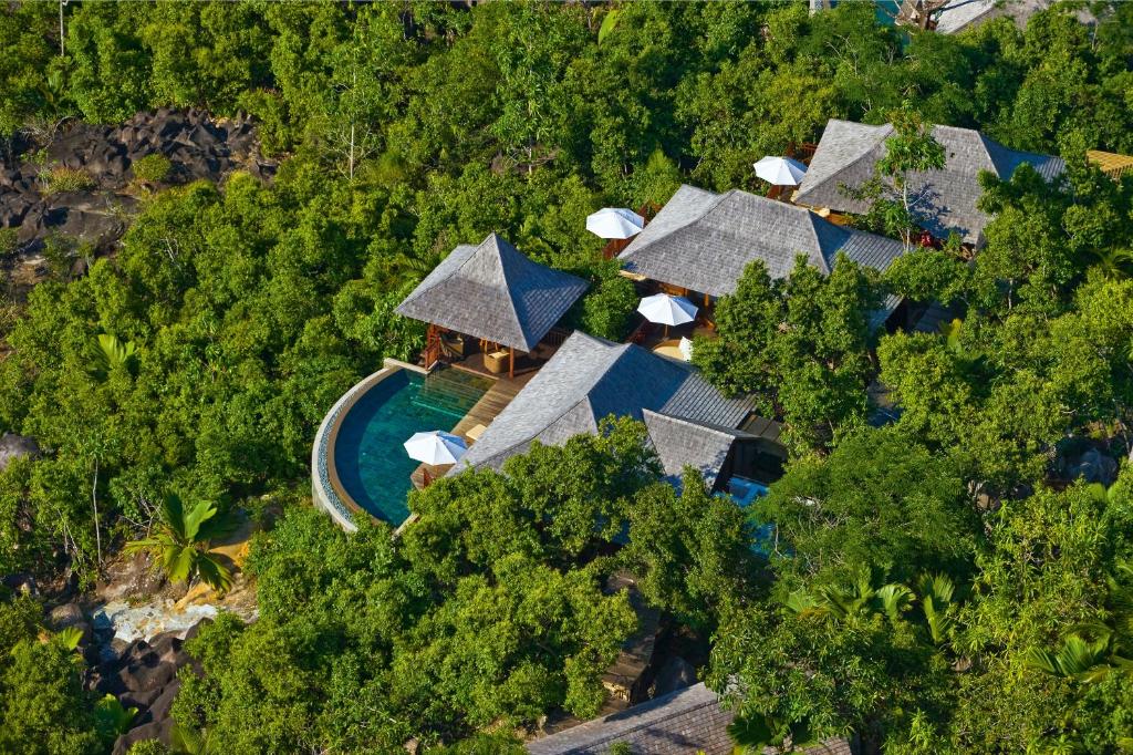 Tropu kūrorts ar elegantiem namiem, kas iekārtoti zaļajā ainavā, un peldbaseins, kas ieskauts tropiskajā augļudārzā.