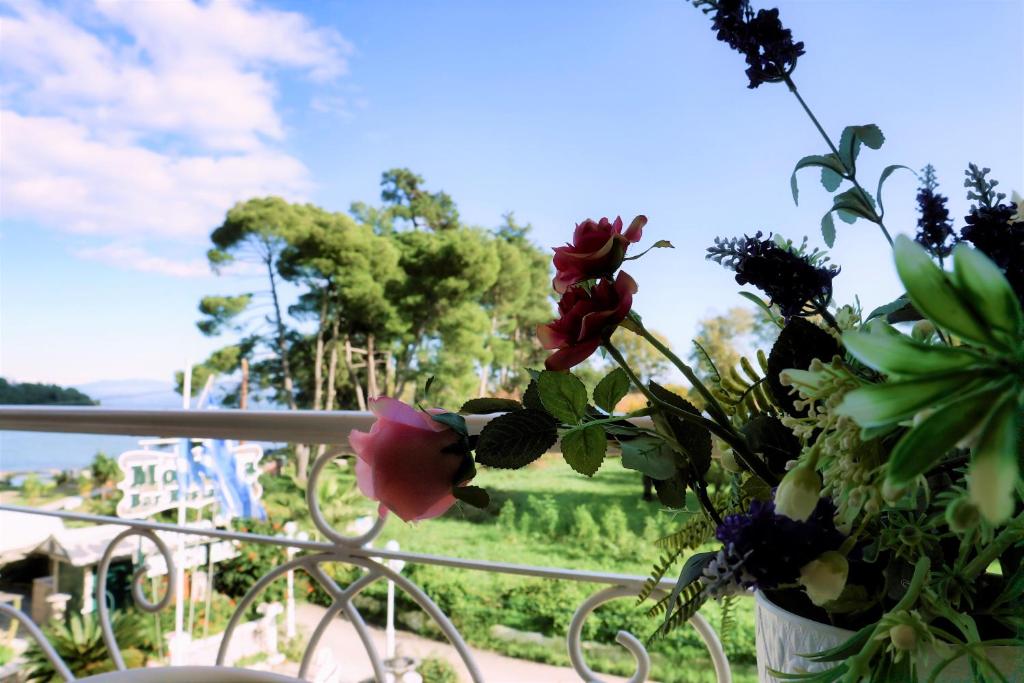 Ziedu kompozīcija uz balkona ar skatu uz dabu un ūdeni, radot mierīgu un relaksējošu atmosfēru.