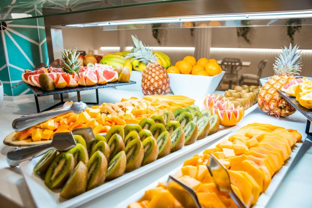 Krāsains augļu bufete ar dažādiem svaigiem augļiem, tostarp ananāsiem, apelsīniem, greipfrūtiem, kiwi un mango. Ideāla izvēle veselīgām brokastīm vai uzkodām.