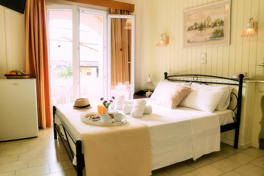 Mūsdienīga viesnīcas istaba ar gultu, augļu grozu un brokastu galdu, kas izgaismota ar dabīgu gaismu no logiem. Svaigs un izsmalcināts interjers nodrošina relaksējošu atmosfēru.