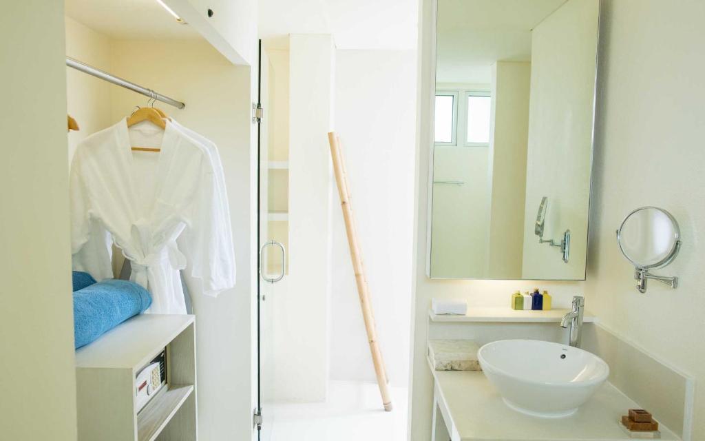 Gaiša un moderna vannas istaba ar skapīti, dvieļiem un spoguļiem, radot relaksējošu atmosfēru. Eleganta dizaina elementu kombinācija nodrošina komfortu un stilu.