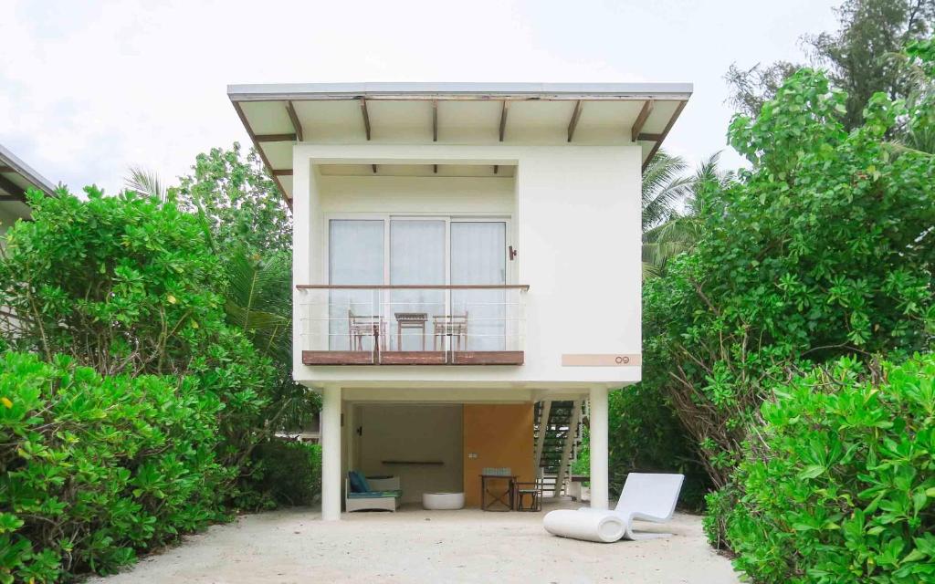 Mūsdienīga brīvdienu māja ar balkonu, iestādīta vidē ar zaļiem krūmiem un tropisku veģetāciju. Ideāla vieta atpūtai pie jūras.