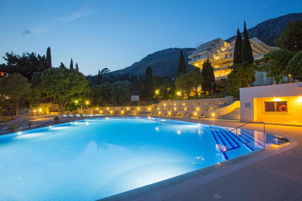 Baseins ar apgaismojumu un kalnu fonā, atpūtas zona ar sauļošanās krēsliem. Vakarā, kad ir zemas gaismas un zila ūdens.