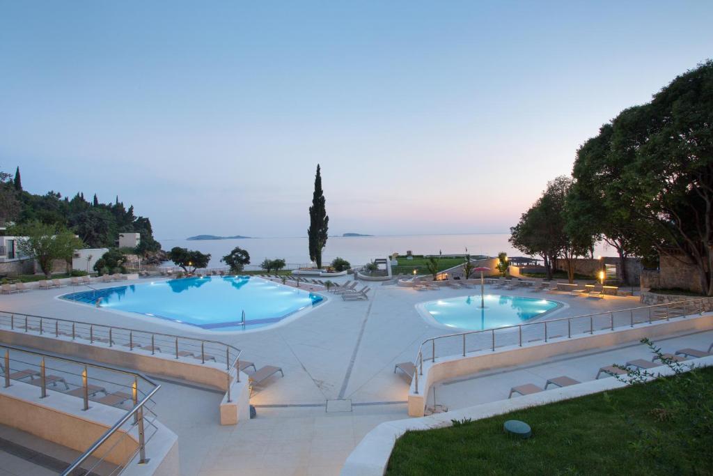 Mūsdienīgs baseins ar skatu uz jūru, apņemts ar sauļošanās krēsliem un zaļo dabu, radot relaksējošu atmosfēru. Vakarā gaisma piešķir ainavai burvību.