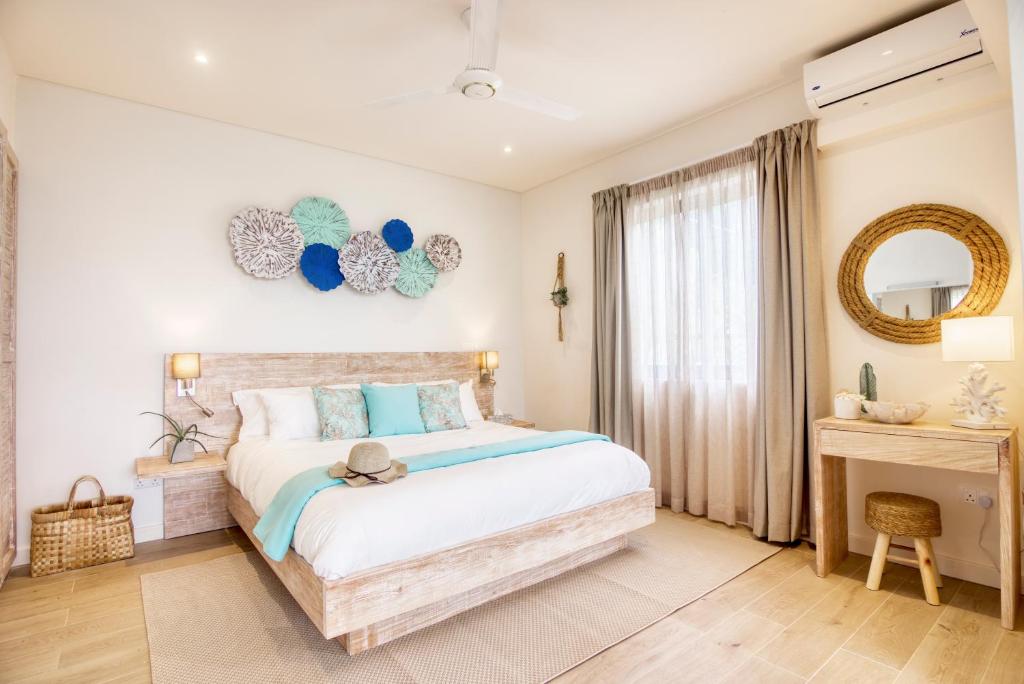 Mūsdienīgs guļamistabas interjers ar gultu, dekoratīviem elementiem uz sienas un dabīgiem toņiem. Telpā ir daudz gaismas un elegants koka mēbeļu risinājums.