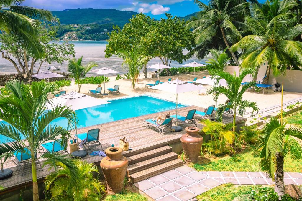 Luksusīgs atpūtas komplekss ar baseinu, sauļošanās krēsliem un palmu kokiem, kas piedāvā skaistus skatus uz pludmali un kalniem. Ideāla vieta relaksācijai un atpūtai.