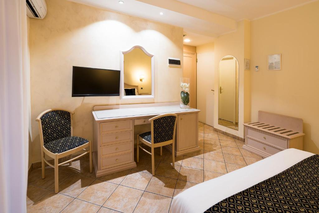 Mūsdienīga viesnīcas numura iekārtojums ar gultu, darba galdu, divām krēslām un televizoru. Numurā ir arī spogulis un skapis, radot komfortablu atmosfēru.