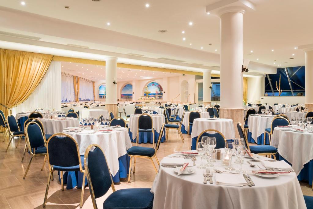 Elegants restorāns ar klātām galdiem, zilo un baltu krāsu kombināciju un izsmalcinātu interjeru, piemērots svinībām un pasākumiem. Apgaismojums rada patīkamu atmosfēru, kas aicina apmeklētājus baudīt maltītes.