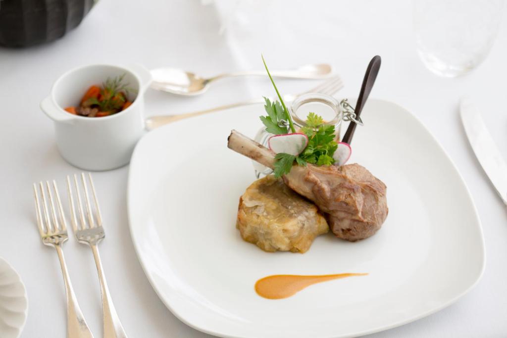 Gatavošanas māksla, eleganti pasniegta maltīte ar jēra gaļas kotleti, garnējumu un dārzeņu salātiem.