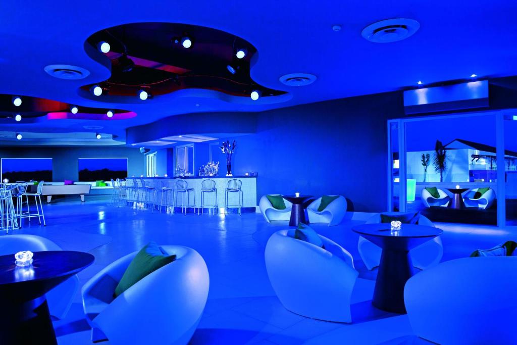 Moderns bārs ar zilu apgaismojumu, stilīgām mēbelēm un elegantu interjeru, radot relaksējošu atmosfēru. Ideāla vieta vakara pavadīšanai ar draugiem.