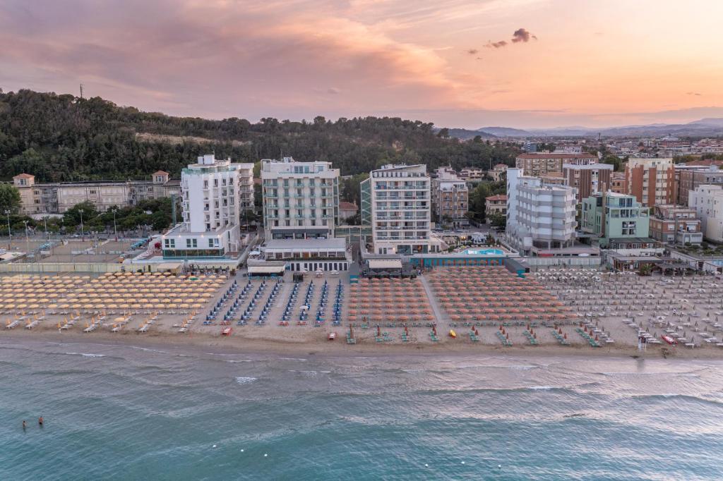 Pludmales ainava ar viesnīcām un sauļošanās krēsliem, saulriets rada mierīgu atmosfēru.