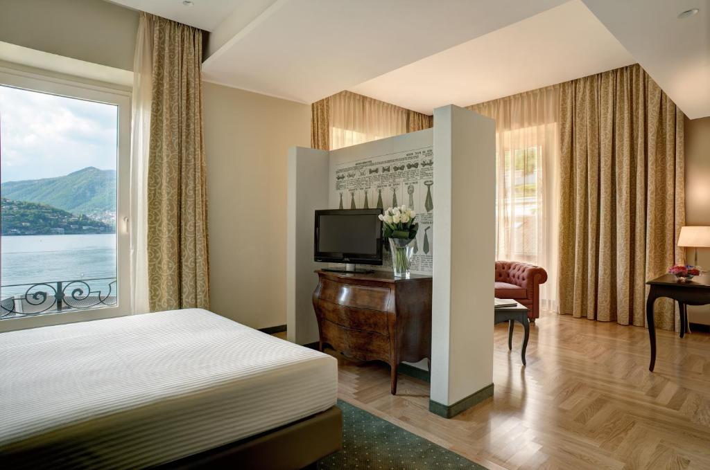 Mūsdienīgs viesnīcas numurs ar skatu uz ezeru, kas apvieno elegantu interjeru un dabas elementus. Telpā ir gulta, televizors un stils, kas nodrošina komfortu un relaksāciju.