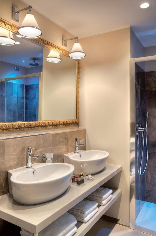 Mūsdienīgs vannas istabas dizains ar divām stilīgām izlietnēm, spoguļu apgaismojumu un dušu. Eleganta un funkcionāla telpa, kas nodrošina komfortu un estētiku.