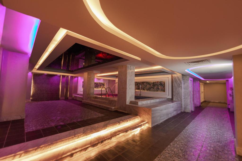 Mūsdienīgs spa interjers ar maigu apgaismojumu un relaksējošu atmosfēru, kurā ir peldbaseins un akmens apdares elementi.