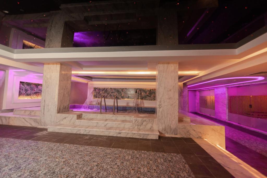 Mūsdienīgs spa ar marmora elementiem un rozā apgaismojumu, radot relaksējošu atmosfēru. Ūdens elementi un modernas arhitektūras detaļas piešķir telpai unikālu izskatu.