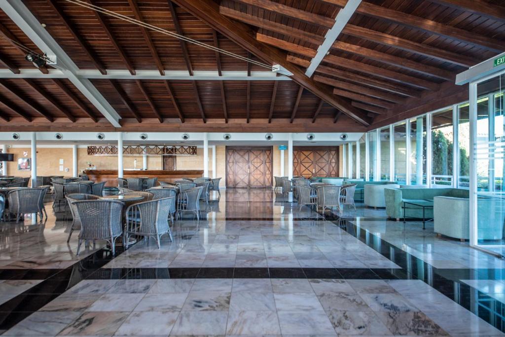 Mūsdienīgs viesnīcas vestibils ar koka griestiem un marmora grīdu, ietverot ērtas sēdvietas un bāra zonu. Gaisma un plašums rada relaksējošu atmosfēru.